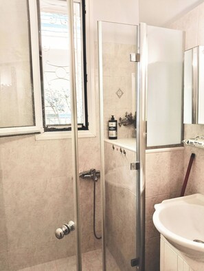 A bathroom with a glass shower enclosure, a sink, and a mirror. - Marousi Residence With Garden (Marousi)