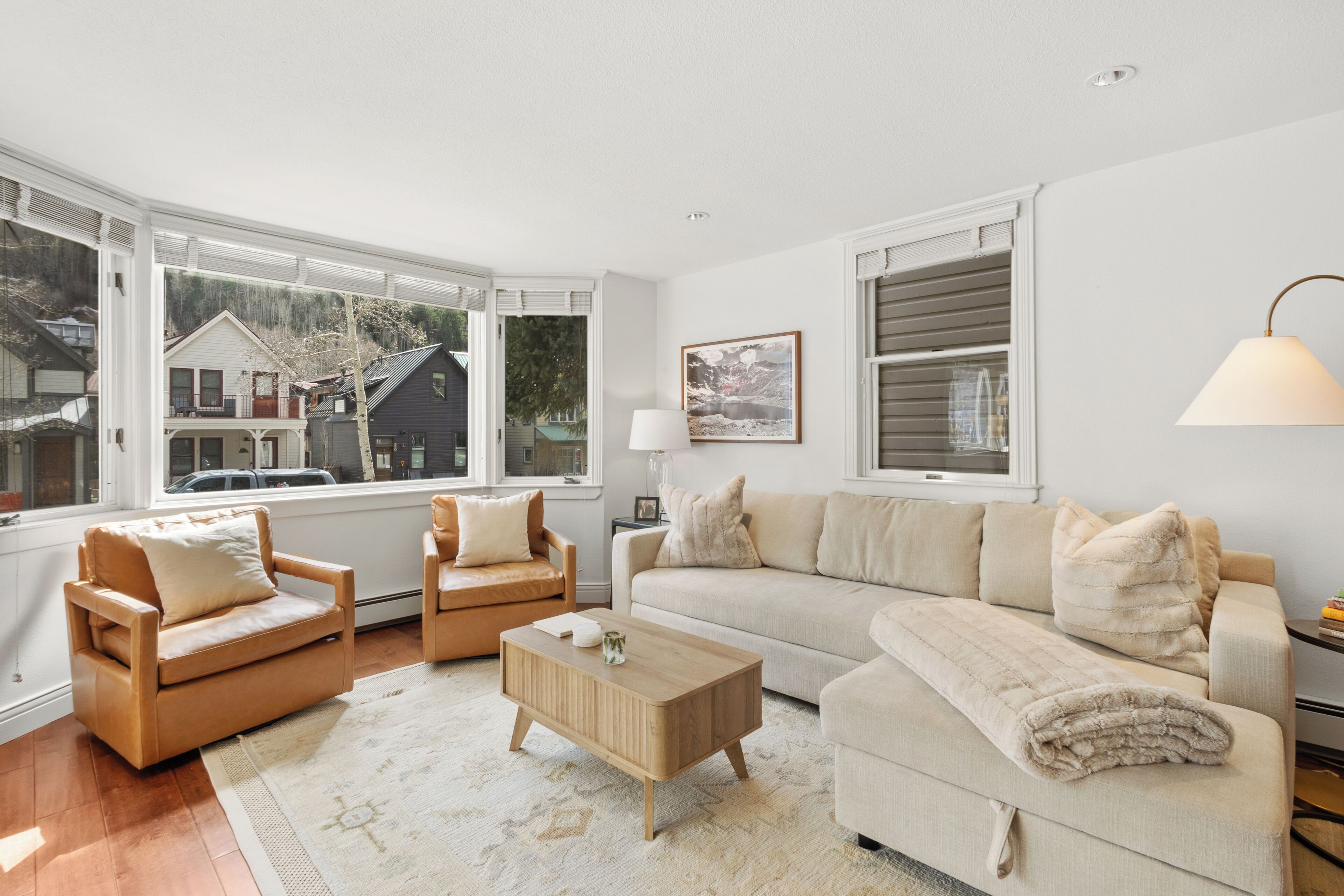 Un salon comprenant un canapé, deux fauteuils, une table basse et de grandes fenêtres.