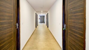 A long, narrow hallway with wooden doors on both sides, leading to a room at the end. - Super Townhouse SR Nagar Metro Hyderabad (Hyderabad)