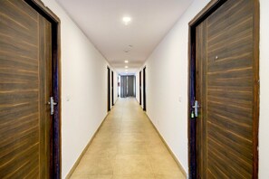 A long, narrow hallway with wooden doors on both sides, leading to a room at the end. - Super Townhouse SR Nagar Metro Hyderabad (Hyderabad)