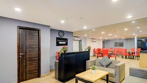 A reception area with a wooden door, a black reception desk, a clock, and red chairs in the background. - Super Townhouse SR Nagar Metro Hyderabad (Hyderabad)