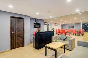 A reception area with a wooden door, a black reception desk, a clock, and red chairs in the background. - Super Townhouse SR Nagar Metro Hyderabad (Hyderabad)