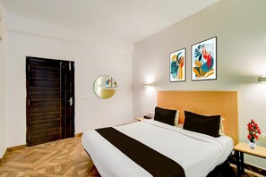 Una habitación de hotel con una cama, una mesita de noche, un espejo y dos cuadros colgados en la pared.