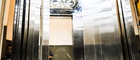 An elevator with a metallic interior and reflective surfaces.