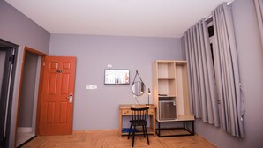 A room with a wooden desk, a chair, a mirror, a television, and a wardrobe. - 1991 Boutique Hotel Phan Thiet (Phu Thuy)