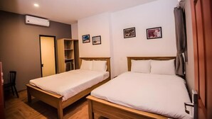 A room with two wooden beds, a wardrobe, a shelf with items, and a door. - 1991 Boutique Hotel Phan Thiet (Phu Thuy)