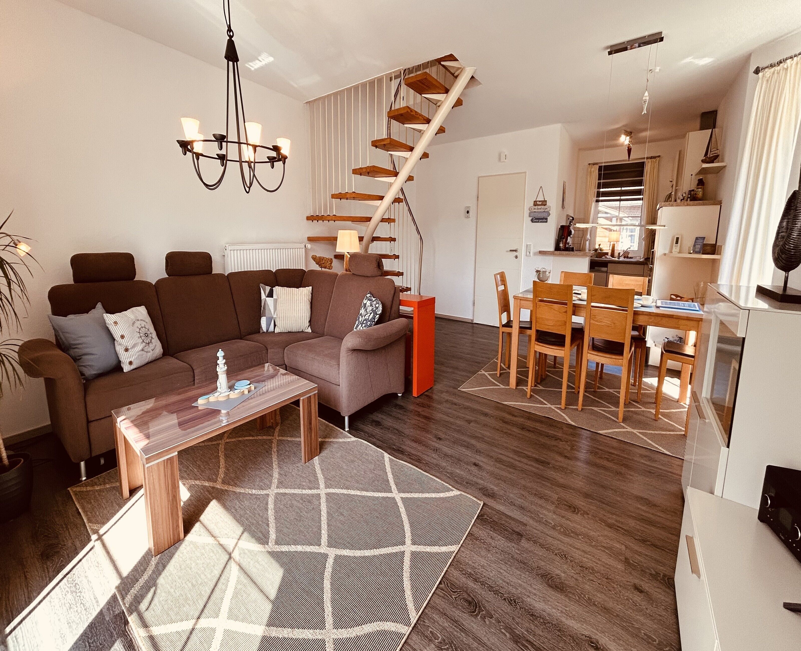 Ein modernes Wohnzimmer mit Sofa, Couchtisch und einem Essbereich mit Stühlen und Tisch.