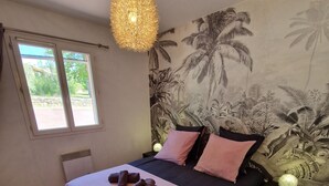 A bedroom with a bed, a window, a wall tapestry, and a hanging light fixture. - Villa Oliveraie - Olive Grove Experience (Villecroze)