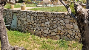 A stone wall, a tree, and a building with a red facade and a tiled roof. - Villa Oliveraie - Olive Grove Experience (Villecroze)