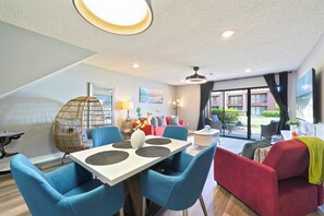 A modern living room with a dining area, a red sofa, and a large window with a view. - Remodeled 2BR townhome just a short walk to the beach with easy Hwy 98 access. Steps to the pool from your back patio. Sleeps 6, pet-friendly (dogs), full kitchen, and close to Pier Park. (Panama City Beach)