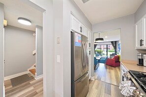 A modern kitchen with a stainless steel refrigerator, a dining area with blue chairs, and a red sofa. - Remodeled 2BR townhome just a short walk to the beach with easy Hwy 98 access. Steps to the pool from your back patio. Sleeps 6, pet-friendly (dogs), full kitchen, and close to Pier Park. (Panama City Beach)