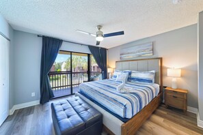 A bedroom with a large bed, a ceiling fan, a bench, a nightstand, and a view through a sliding door. - Remodeled 2BR townhome just a short walk to the beach with easy Hwy 98 access. Steps to the pool from your back patio. Sleeps 6, pet-friendly (dogs), full kitchen, and close to Pier Park. (Panama City Beach)