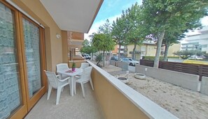 Ein Balkon mit Tisch, Stühlen, einer Topfpflanze und Blick auf die Straße und die Häuser.