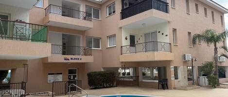 A multi-story residential building with a swimming pool, balconies, and a sign indicating 'Block 2'.