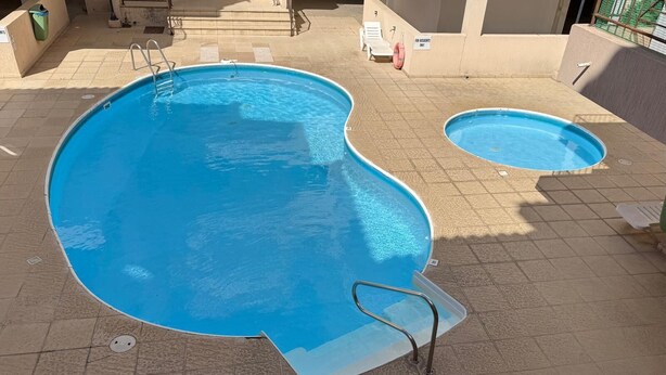 A large outdoor swimming pool with a diving board and a smaller pool nearby. - The Sun Whisper (Chlorakas)
