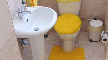 A bathroom with a sink, toilet, and a yellow rug on the floor.