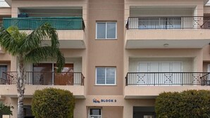 A multi-story building with balconies, a sign reading 'BLOCK 2,' and a palm tree in the foreground. - The Sun Whisper (Chlorakas)
