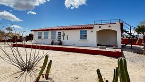 Un edificio blanco con techo rojo y una escalera que lleva a un balcón.