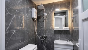 A modern bathroom with a shower, toilet, and sink, all against a marble wall. - Galata Sea Suites (İstanbul)