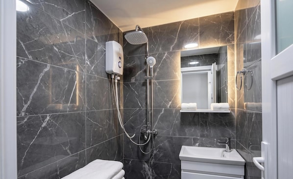 Un bagno moderno con doccia, toilette e lavandino, il tutto su uno sfondo di parete in marmo.
