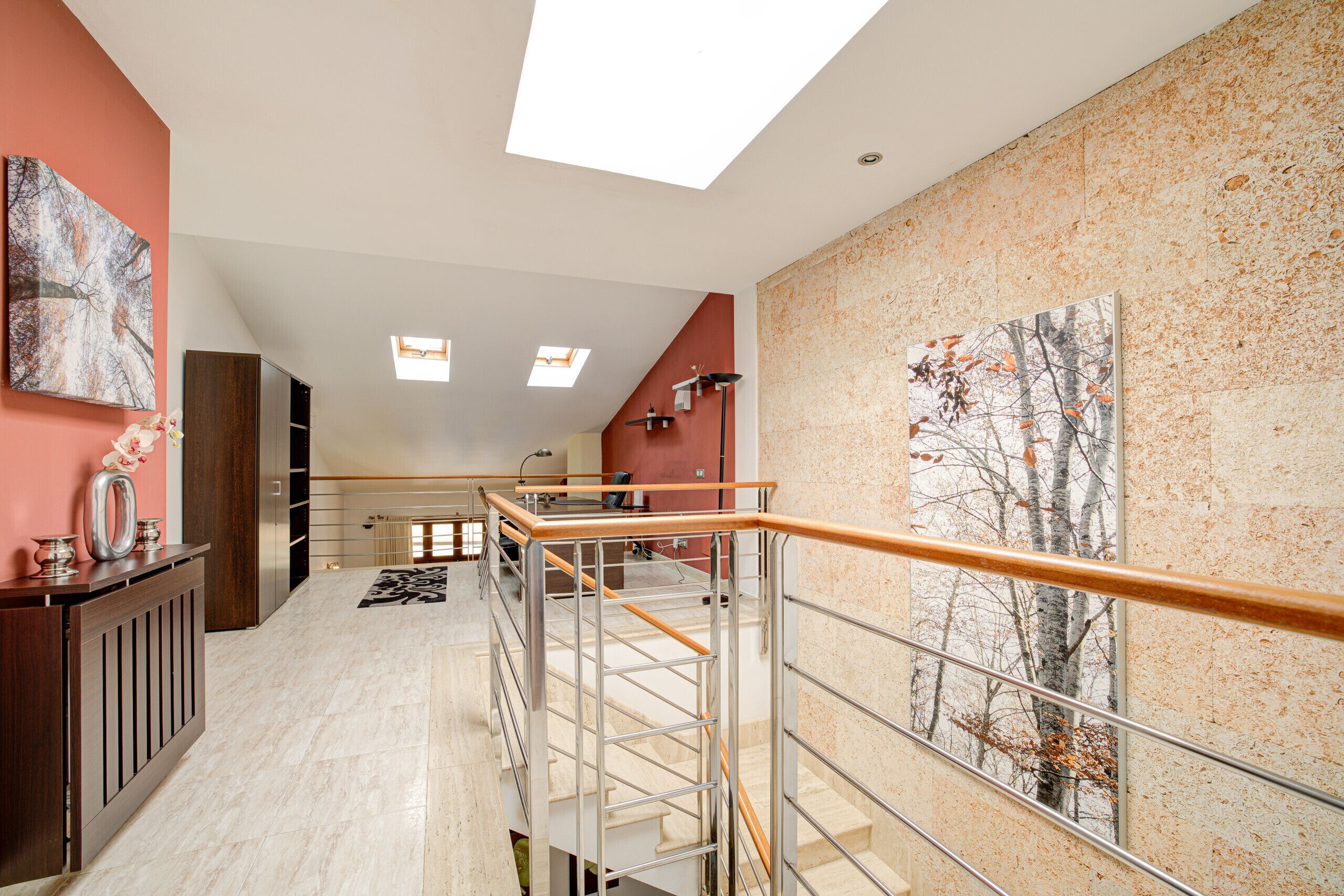 Een modern interieur met een trap, een houten leuning en kunstwerken aan de muur.