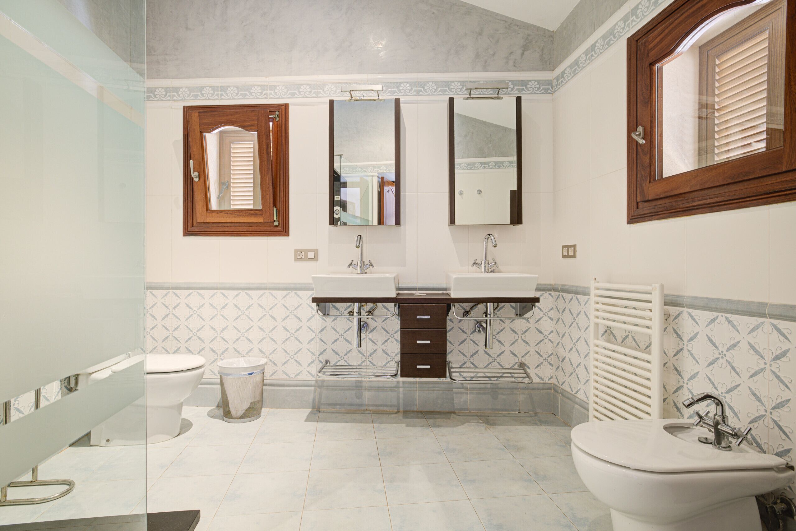 A bathroom with two sinks, a toilet, a mirror, and a window.