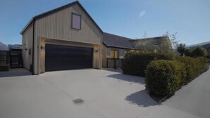 Un bâtiment d’un seul étage doté d’une grande porte de garage, d’une petite structure adjacente avec une fenêtre et d’une allée pavée.