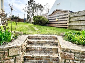 A stone staircase leading up to a wooden deck with a grassy area and a wooden fence. - Plouguerneau Coastal Retreat With Garden (Lampaul-Plouarzel)