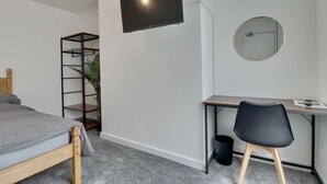 A bedroom with a bed, a desk, a chair, a TV, a mirror, and a plant. - WorkStay Portsmouth Contractor House (Portsmouth)