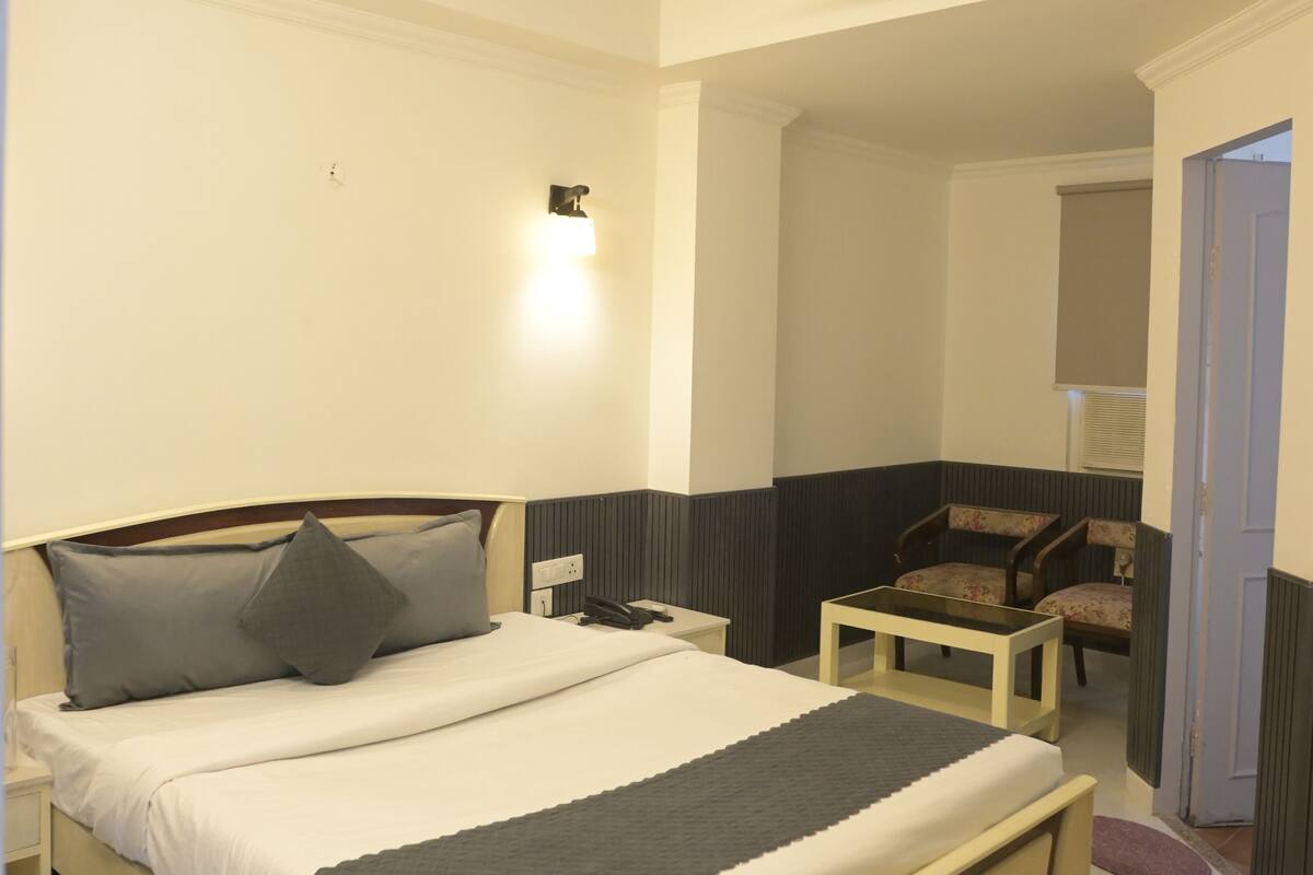 A bedroom with a bed, bedside table, chair, and a ceiling fan.
