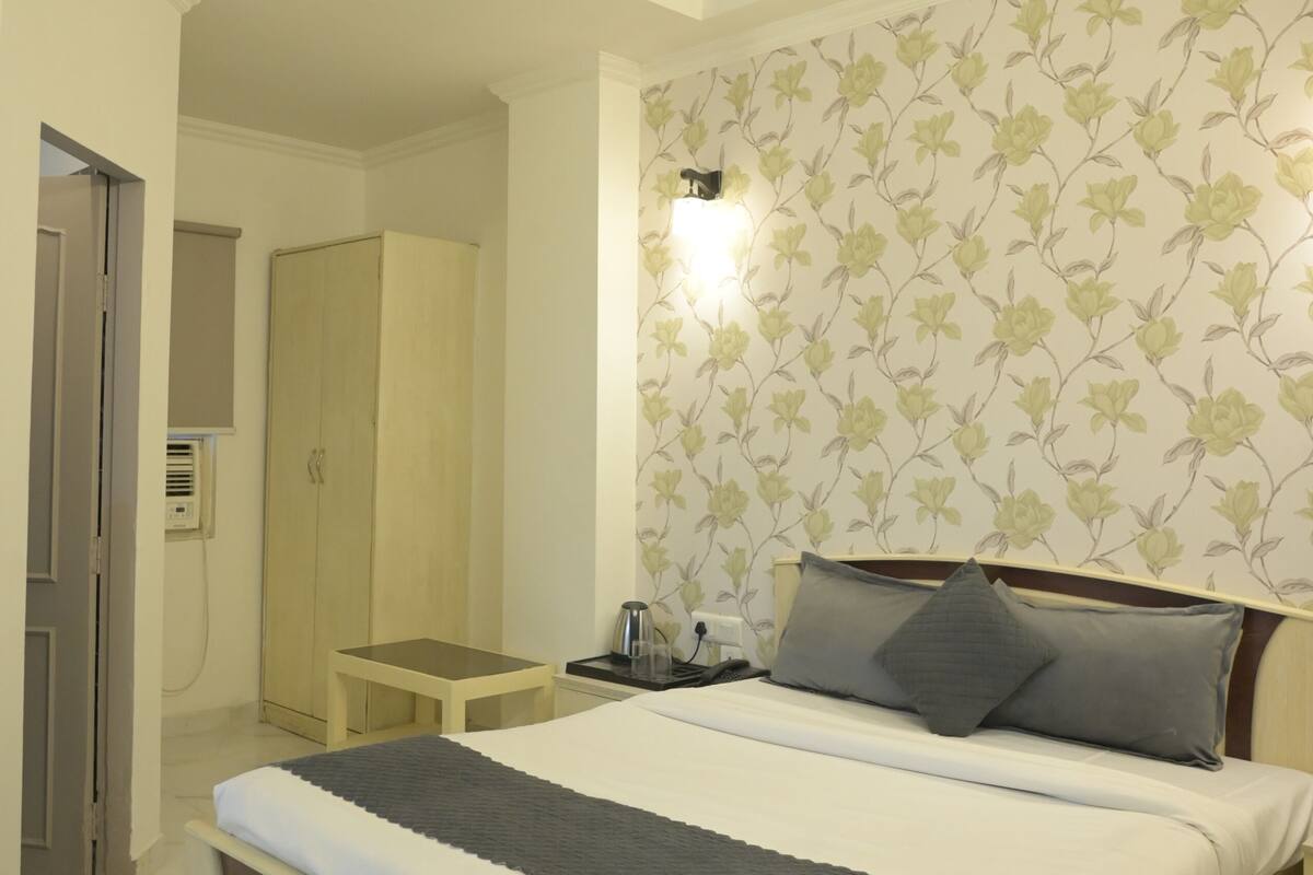 A bedroom with a bed, bedside table, nightstand, lamp, and a ceiling fan.