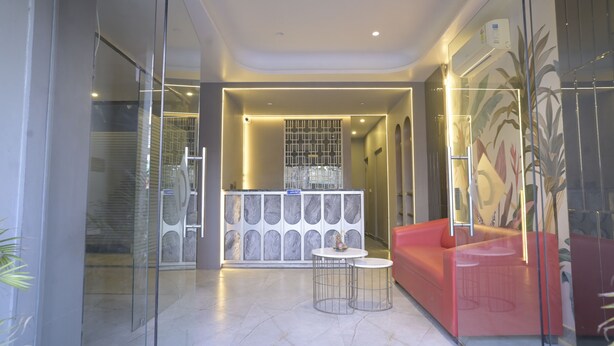 A modern lobby with a reception desk, a red sofa, and a glass partition. - The Tulip Regency (Jaipur)