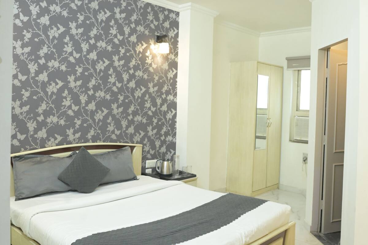 A bedroom with a bed, a ceiling fan, a nightstand, a wardrobe, and a bathroom door.