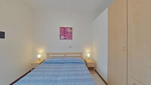 Ein Schlafzimmer mit einem Bett, zwei Nachttischen, einem Schrank und einem floralen Wandbild.