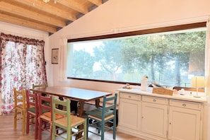 A dining area with a wooden table and chairs, a window with a view of trees, and a cabinet with a sign on top. - S359 - Sirolo, dependance with garden  (Sirolo)