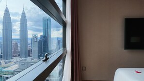 Camera d'albergo con una grande finestra che si affaccia su una vista urbana con grattacieli.