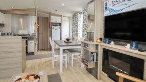 A modern kitchen with a dining area, a TV, and a sign reading 'Lost at Sea'. - Caravan 117 (Great Yarmouth)