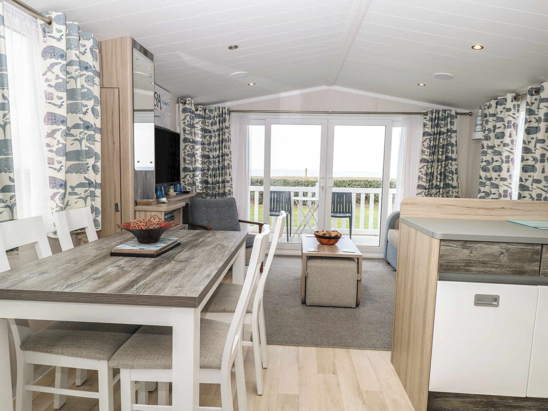 A modern kitchen with a dining area, white cabinetry, and a view of the sea.