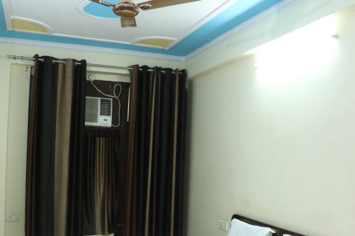 Un dormitorio con una cama, ventilador de techo y ventana con cortinas.