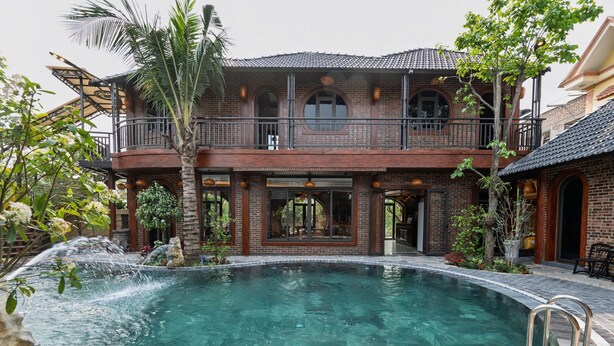 A two-story building with a swimming pool, a balcony, and a waterfall feature. - Tam Coc Green Vibes Retreat (Nam Hoa Lu)