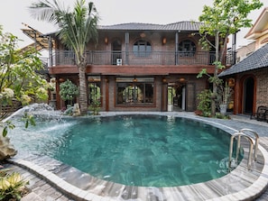 A two-story building with a swimming pool, a balcony, and a waterfall feature. - Tam Coc Green Vibes Retreat (Hoa Lu)