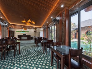 A restaurant with a green and white checkered floor, wooden ceiling, and large windows overlooking a pool. - Tam Coc Green Vibes Retreat (Hoa Lu)