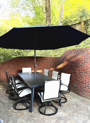 A patio with a brick wall, a table with chairs, and a large umbrella. - World Cup Oasis - adorable 3-bedroom house in idyllic Atlanta neighborhood (Atlanta)