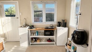 Een compacte keuken met een gootsteen, magnetron, waterkoker en een kleine koelkast.