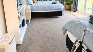 Een slaapkamer met een bed, een nachtkastje, een boekenkast, een radiator en een raam met gordijnen.
