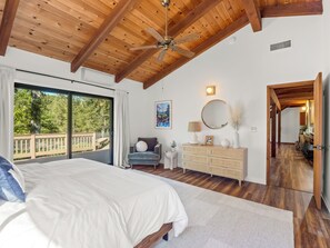 A bedroom with a large bed, a ceiling fan, a dresser, and a view of a balcony. - Brand New! Pool, Hot Tub, BBQ, Fire Pit & Games (Oakhurst)