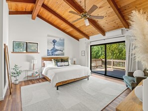 A bedroom with a bed, a ceiling fan, a large window, and a view of the outdoors. - Brand New! Pool, Hot Tub, BBQ, Fire Pit & Games (Oakhurst)