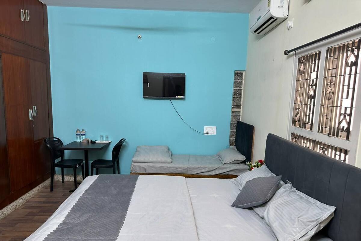 A room with a bed, a desk, a chair, a TV, and a wardrobe.