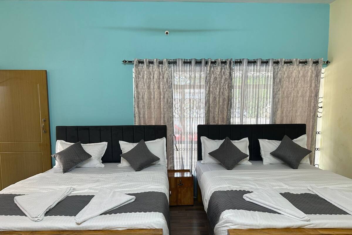 A twin room with two beds, a wooden wardrobe, and a window with curtains.