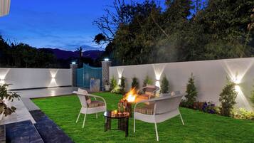 Una veranda esterna con un elemento decorativo a fuoco, posti a sedere e un prato curato.